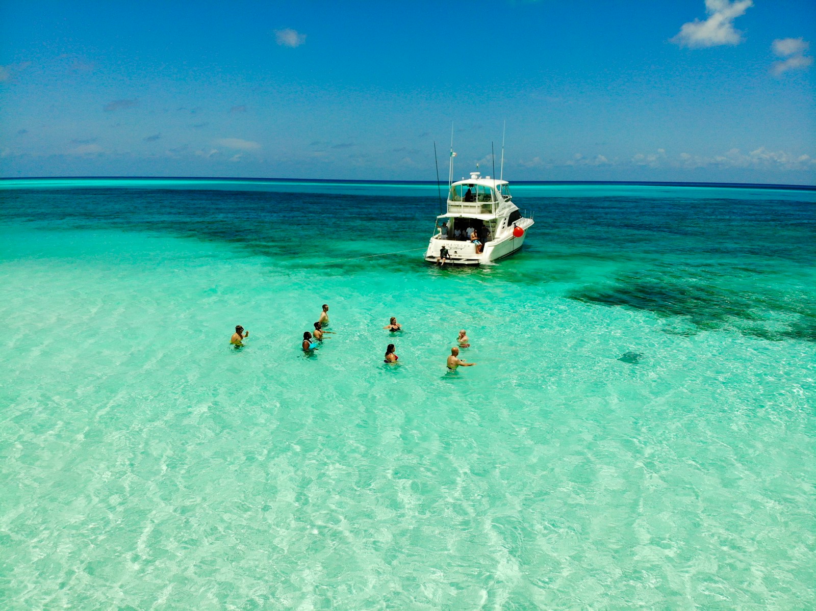 people on body of water across white yacht